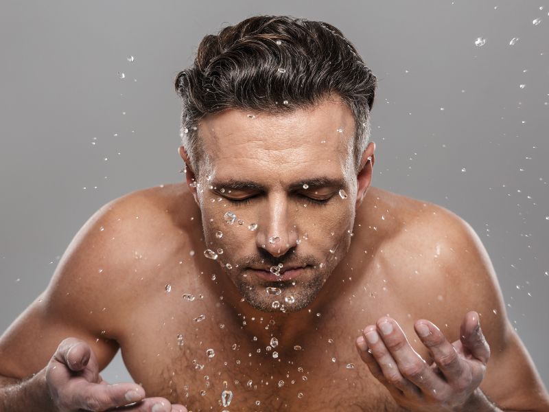 Man splashing water on his face after washing it.